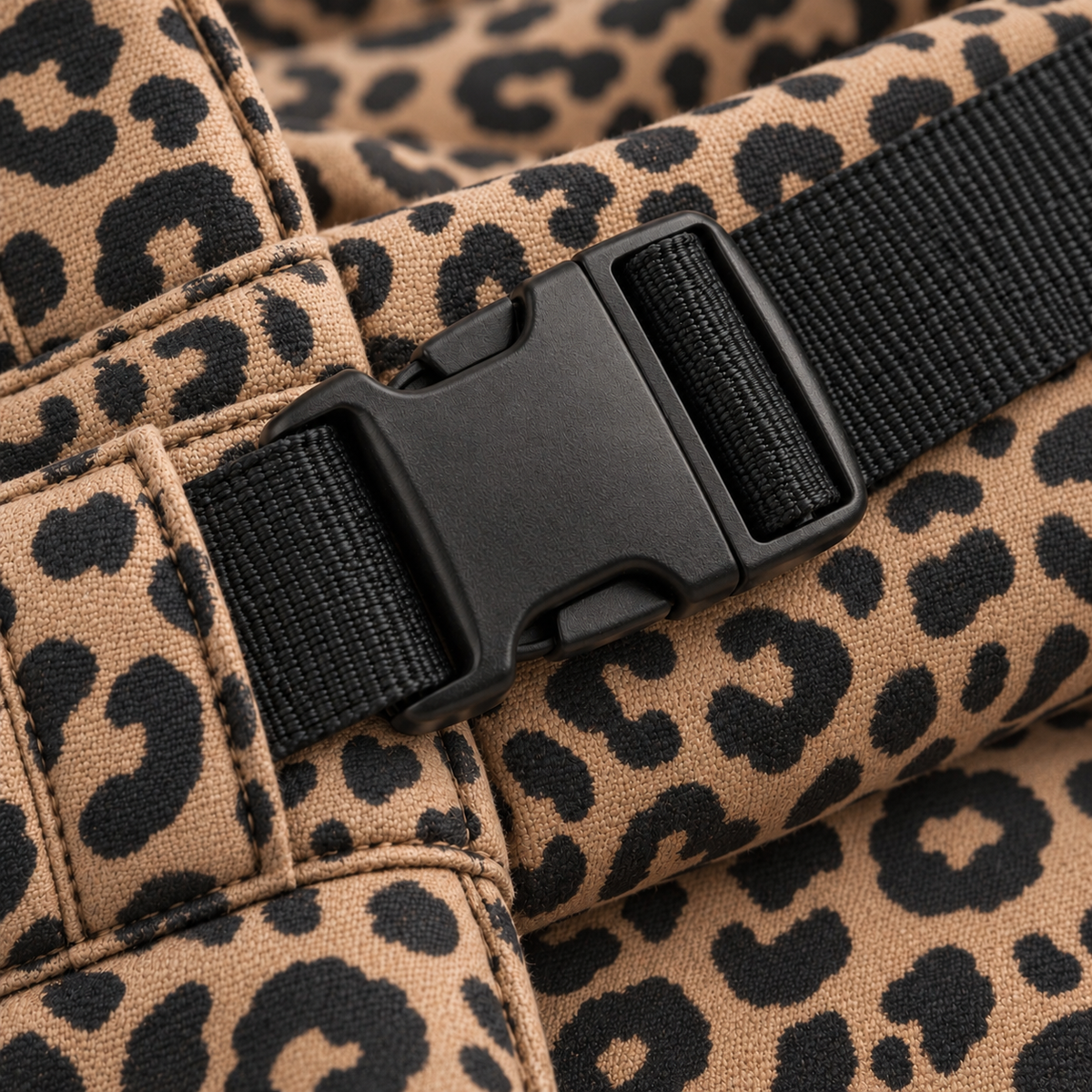 Gros plan sur la boucle de fixation noire d'un porte-bébé BEBEHUGS à motif léopard.